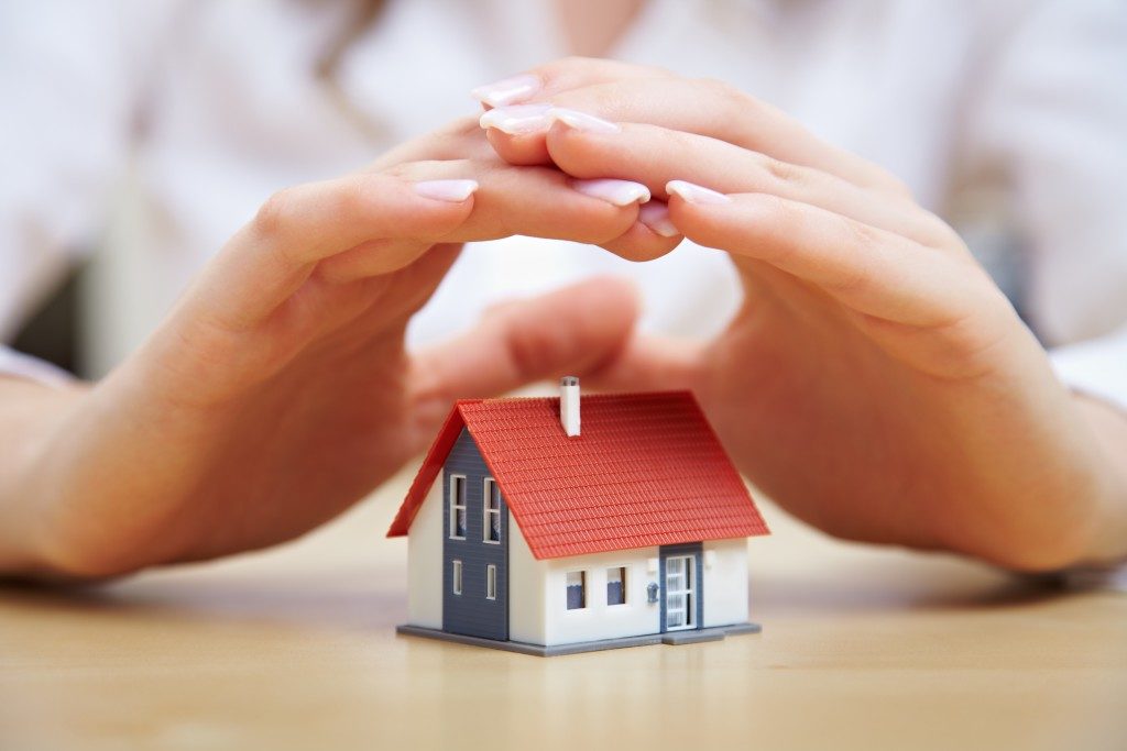person's hand covering a miniature house 