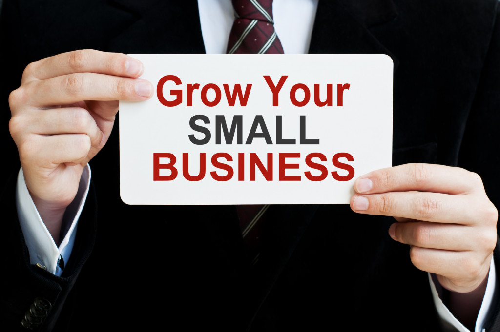 businessman holding a paper with grow your small business written on it